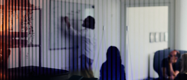 Silhouetten von Personen in Besprechung hinter Glaswand