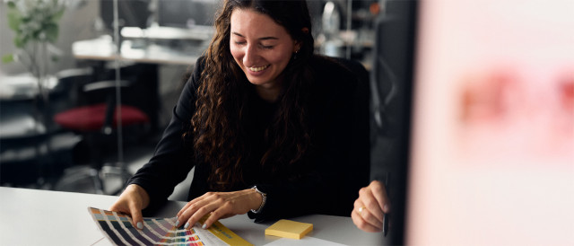 Frau wählt Farben aus einem Farbfächer am Tisch