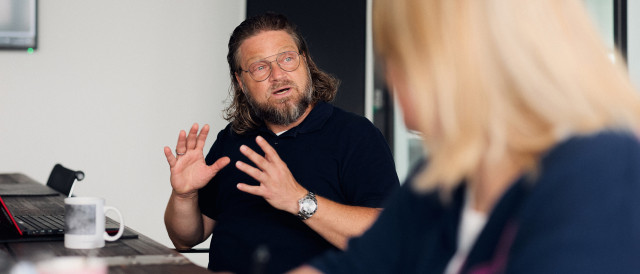 Mann erklärt etwas im Meeting und gestikuliert am Tisch