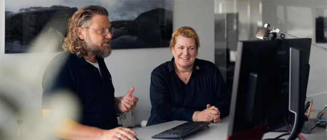 Zwei Kolleg:innen besprechen Inhalte am Monitor im Büro